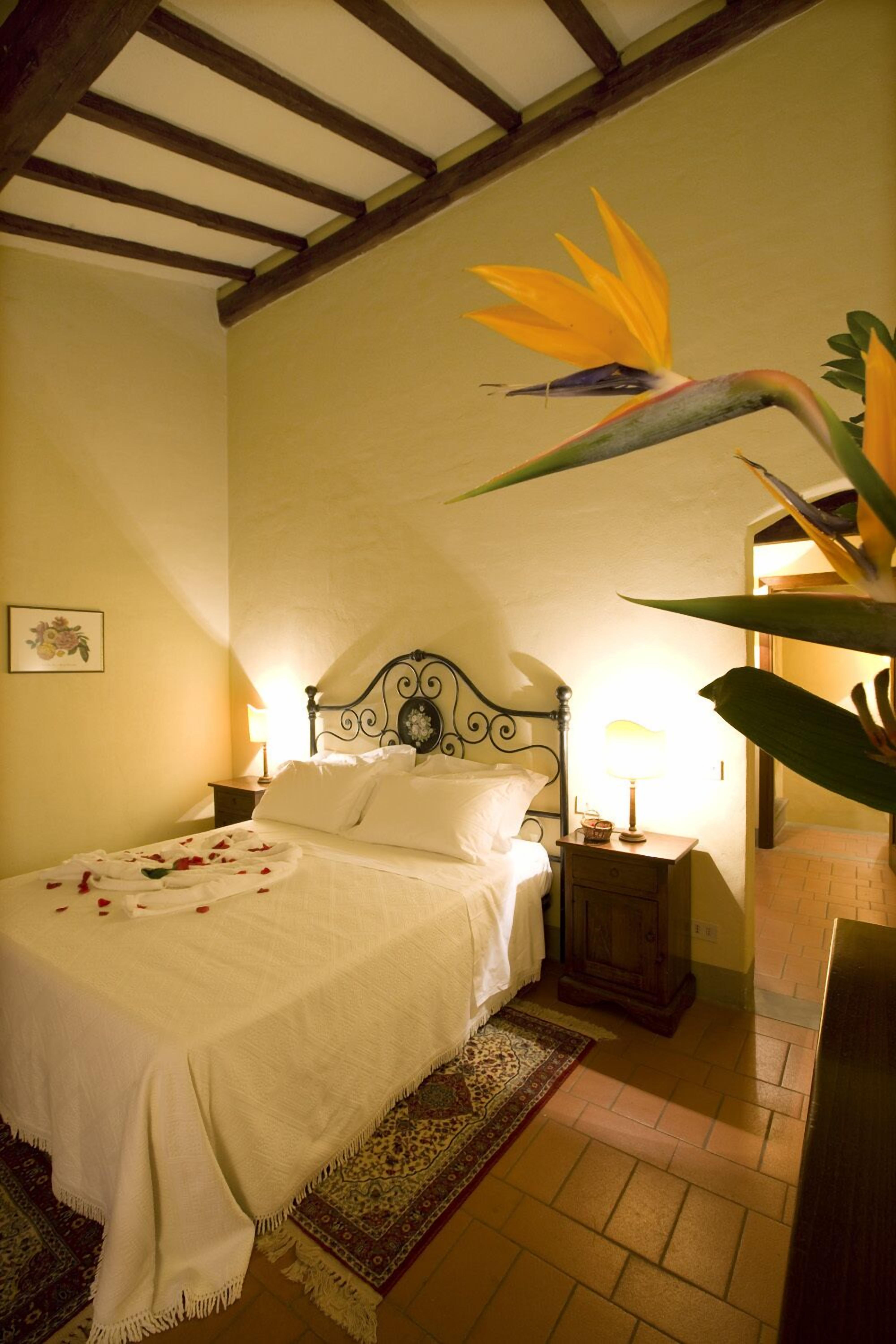 A neatly made bed with white linens, a wooden headboard, and a nightstand with a lamp.