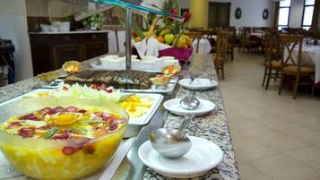 Un bufé con diversos platos y un bol de fruta.