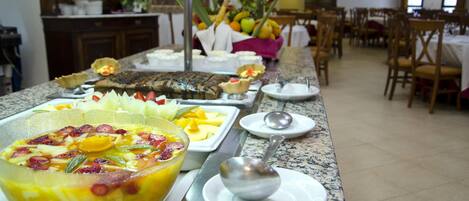 A buffet with various dishes and a fruit bowl.