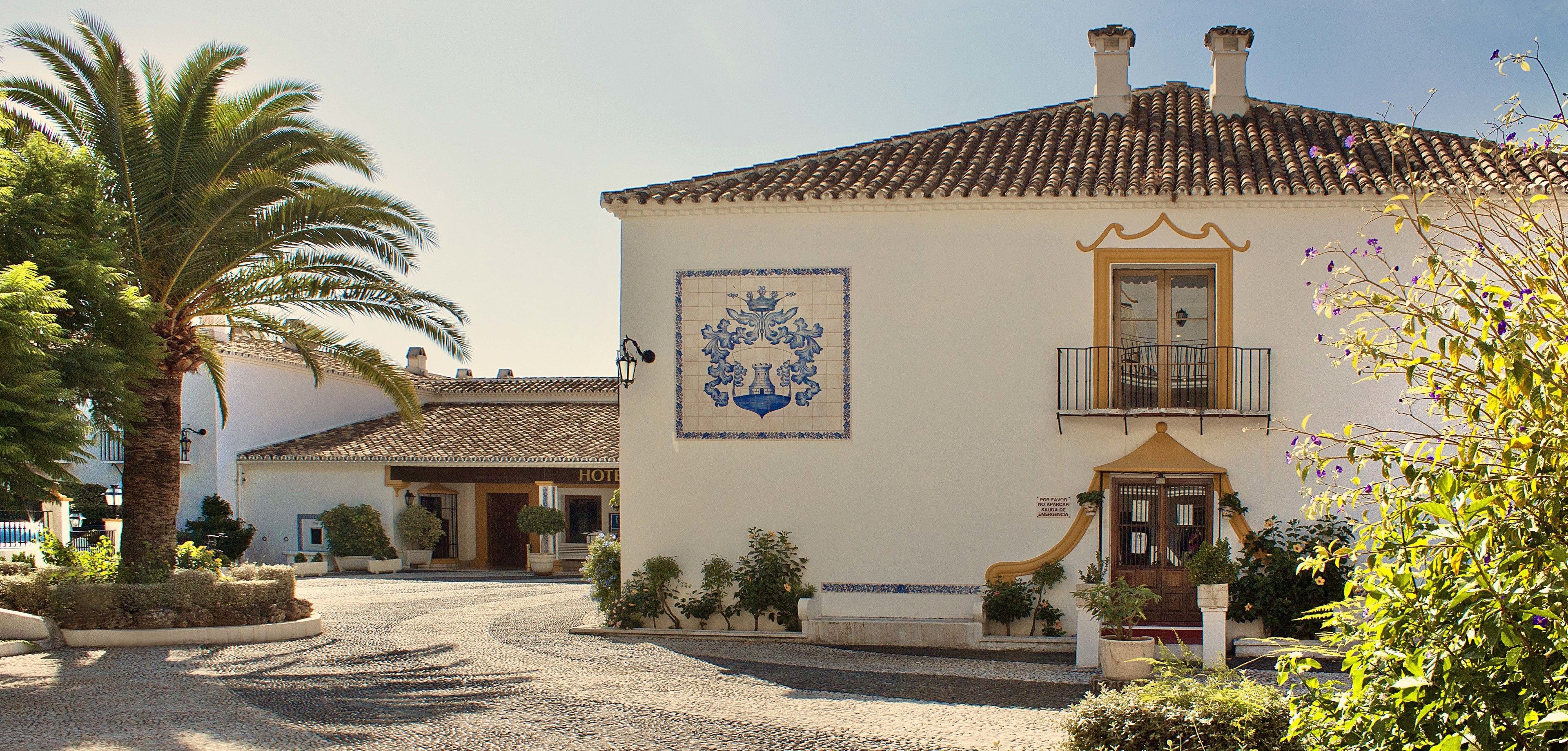 A traditional building with a tiled roof, a balcony with a wrought iron railing, and a decorative tile pattern on the wall.