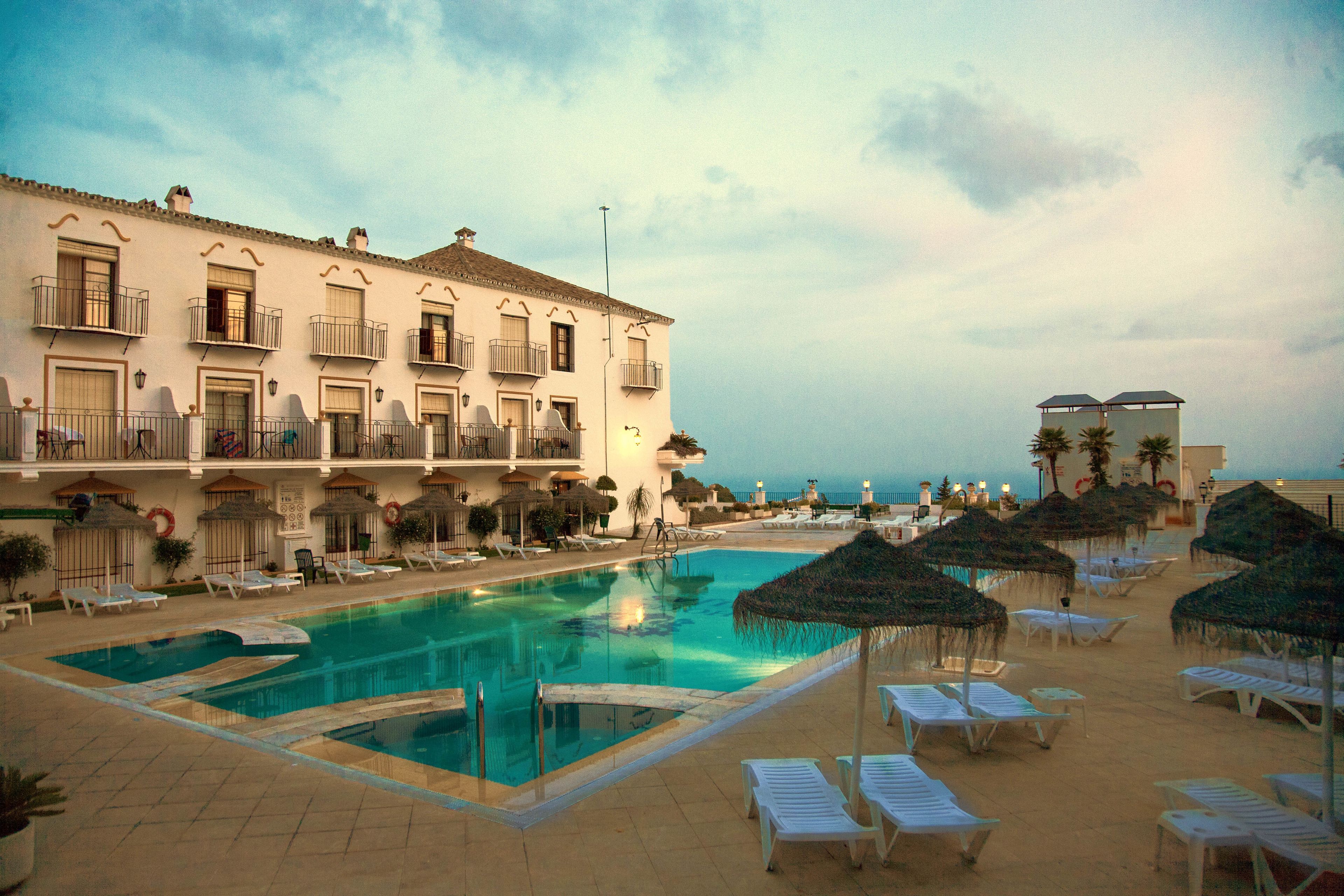 Ett hotell med en swimmingpool, solstolar och parasoller.