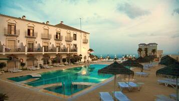 Ett hotell med en swimmingpool, solstolar och parasoller.