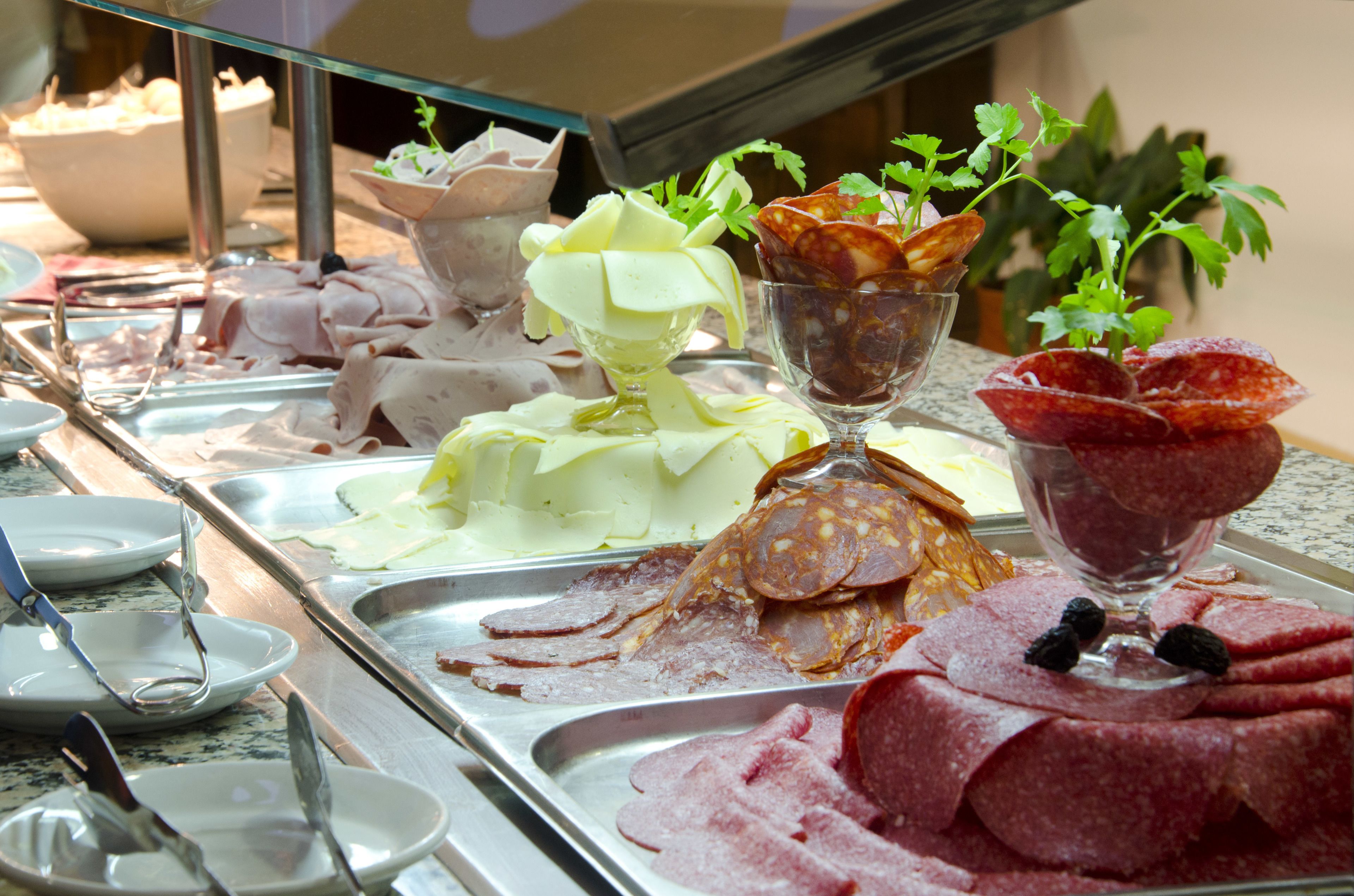 A buffet with various meats and a glass bowl of green salad.