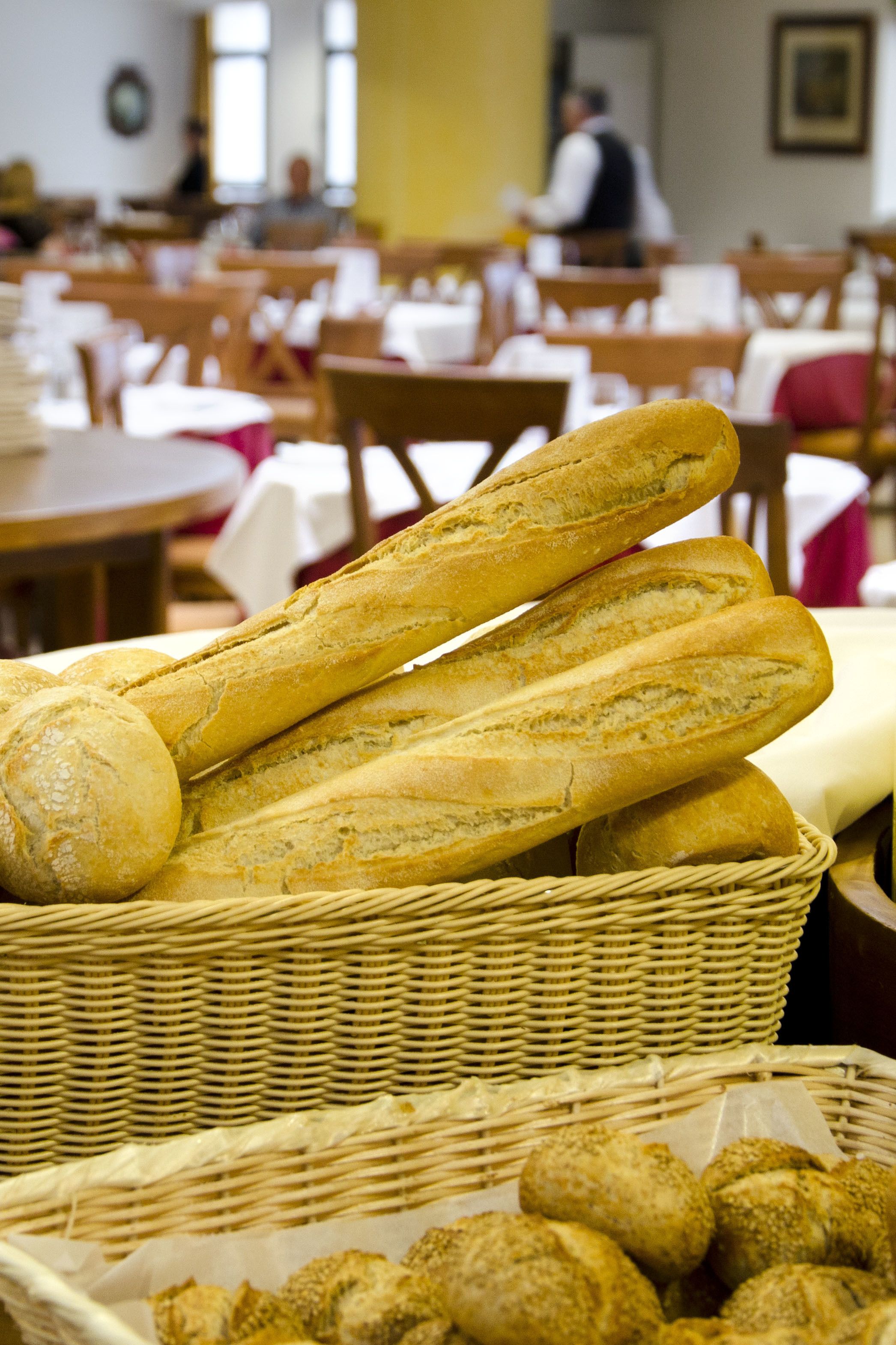 A basket of baguettes and croissants in a restaurant setting.