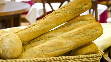 A basket of baguettes and croissants in a restaurant setting.