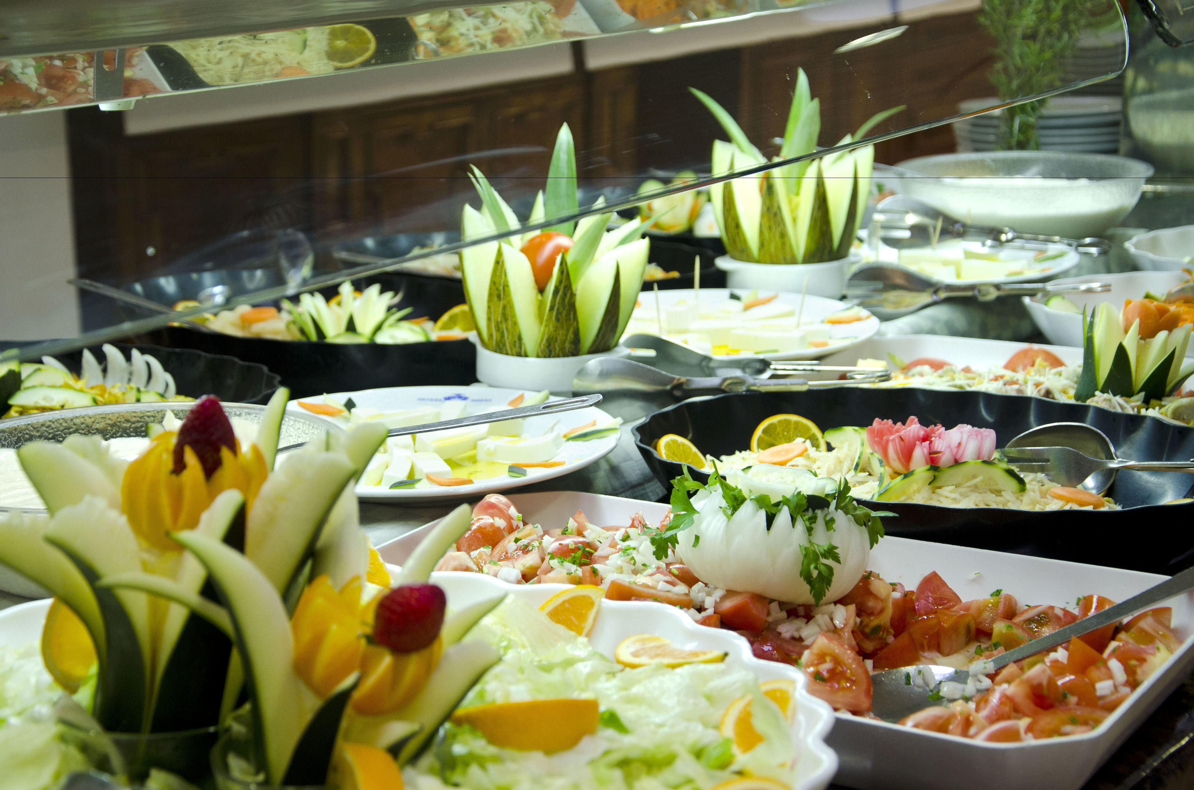 A buffet with various dishes including salads, fruits, and vegetables.