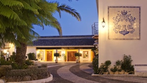 Un hotel con fachada de azulejos, un muro decorativo y una entrada bien iluminada.