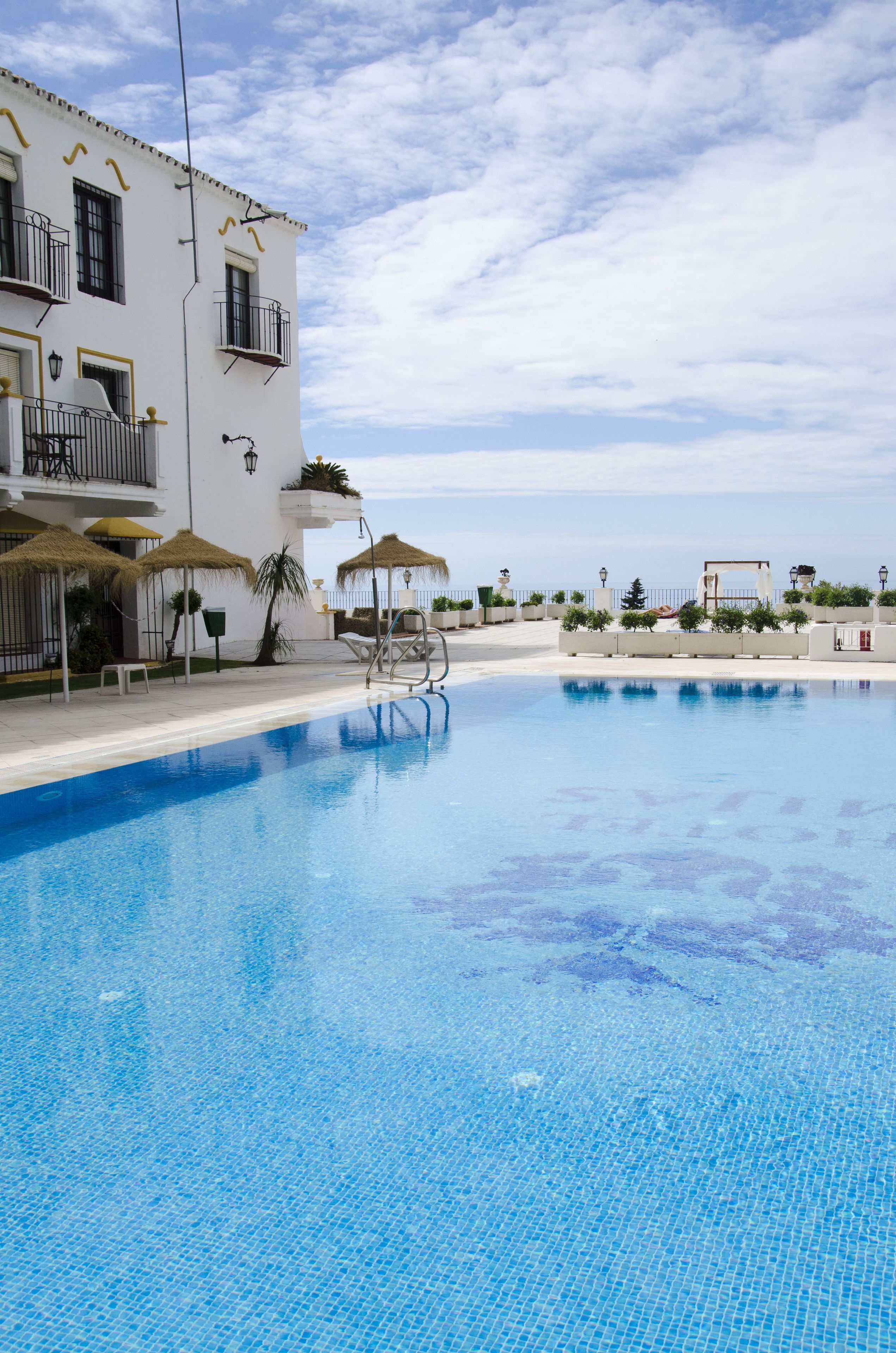 Een buitenzwembad, parasols bij het zwembad en ligstoelen