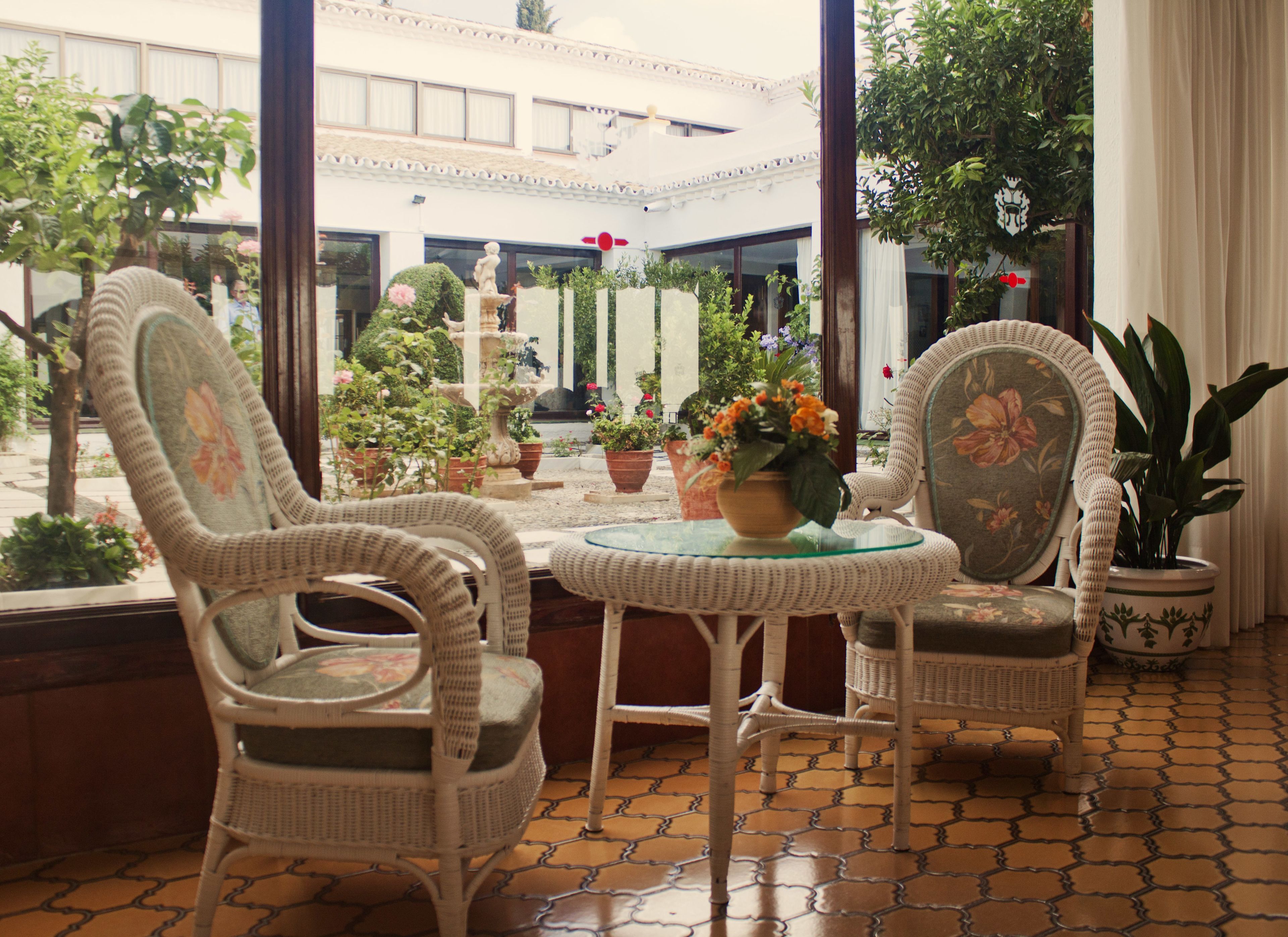 A room with wicker chairs, a glass table, and potted plants.