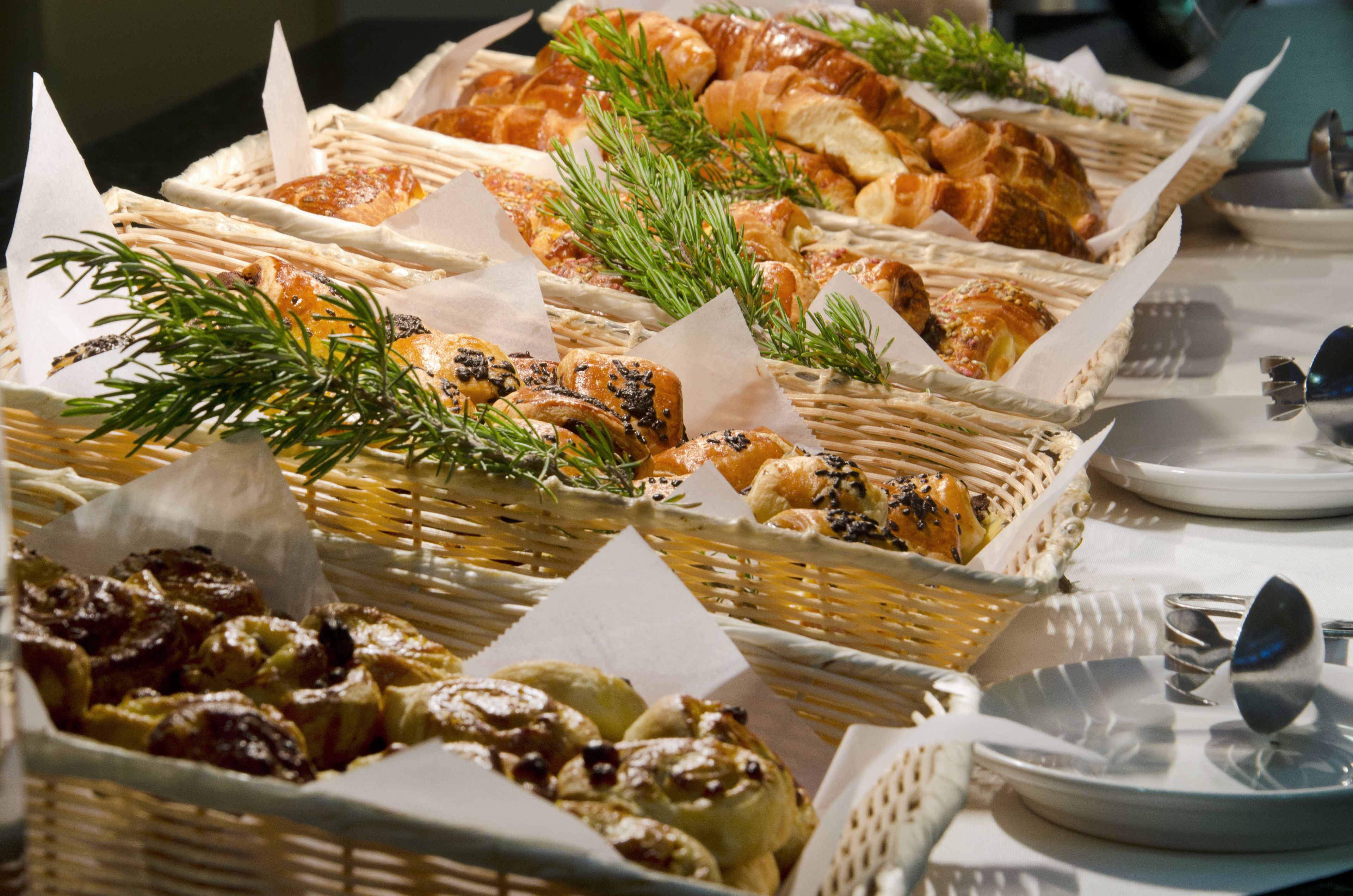 Una mesa de buffet con diversos productos horneados y pasteles exhibidos en cestas.