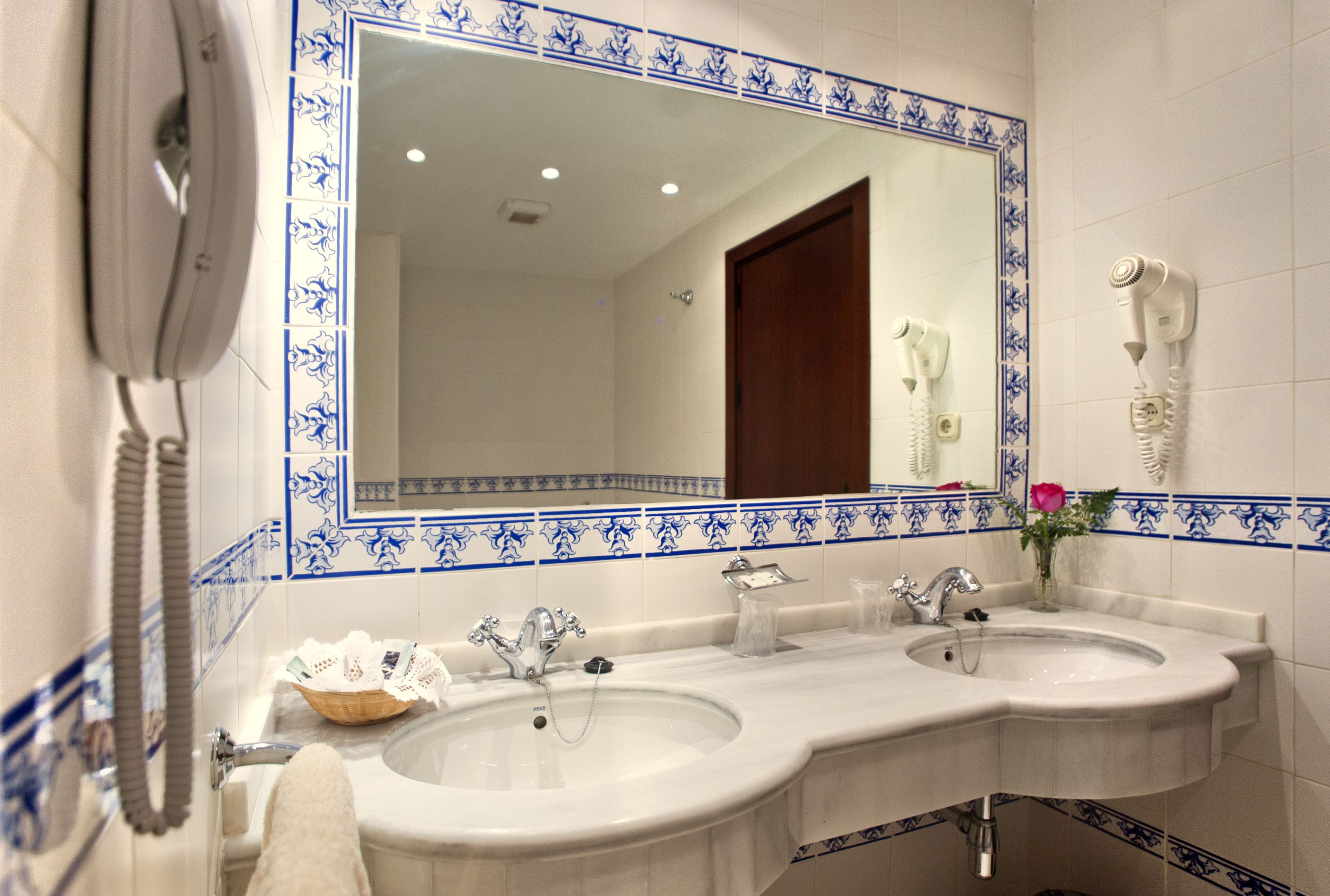 A bathroom with two sinks, a large mirror, and a hairdryer mounted on the wall.