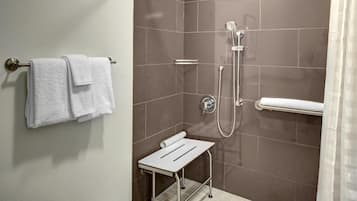 A bathroom with a shower, a towel rack, and a small table.