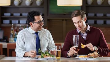 Two men dining at a restaurant with a table set for two, a beer glass, and a plate of food.