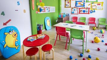 Children can play and learn in this vibrant playroom with a table, chairs, bean bag chair, and educational posters.