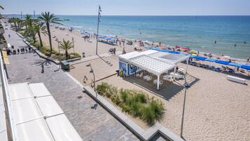 A beachside hotel with a patio area, beach access, and a view of the sea.