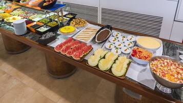 Un buffet con diverse pietanze, tra cui frutta, verdura e dolci.