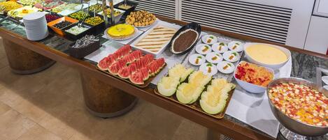 A buffet with various food items including fruits, vegetables, and desserts.
