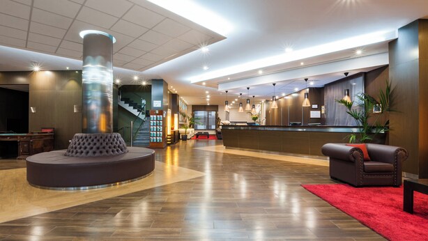 A spacious lobby with a reception desk, a curved seating area, and a staircase.