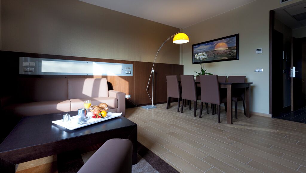 A modern living room with a sofa, coffee table, and dining area.