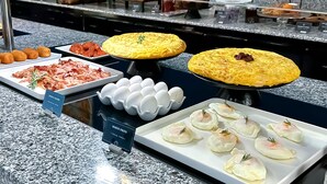 A buffet with various food items including pastries, eggs, and meat.