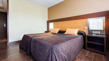 Una habitación de hotel moderna con una cama grande, dos mesitas de noche y un televisor integrado.