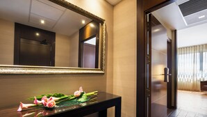 A hotel reception area with a wooden console table, a large mirror, and a decorative arrangement of flowers.