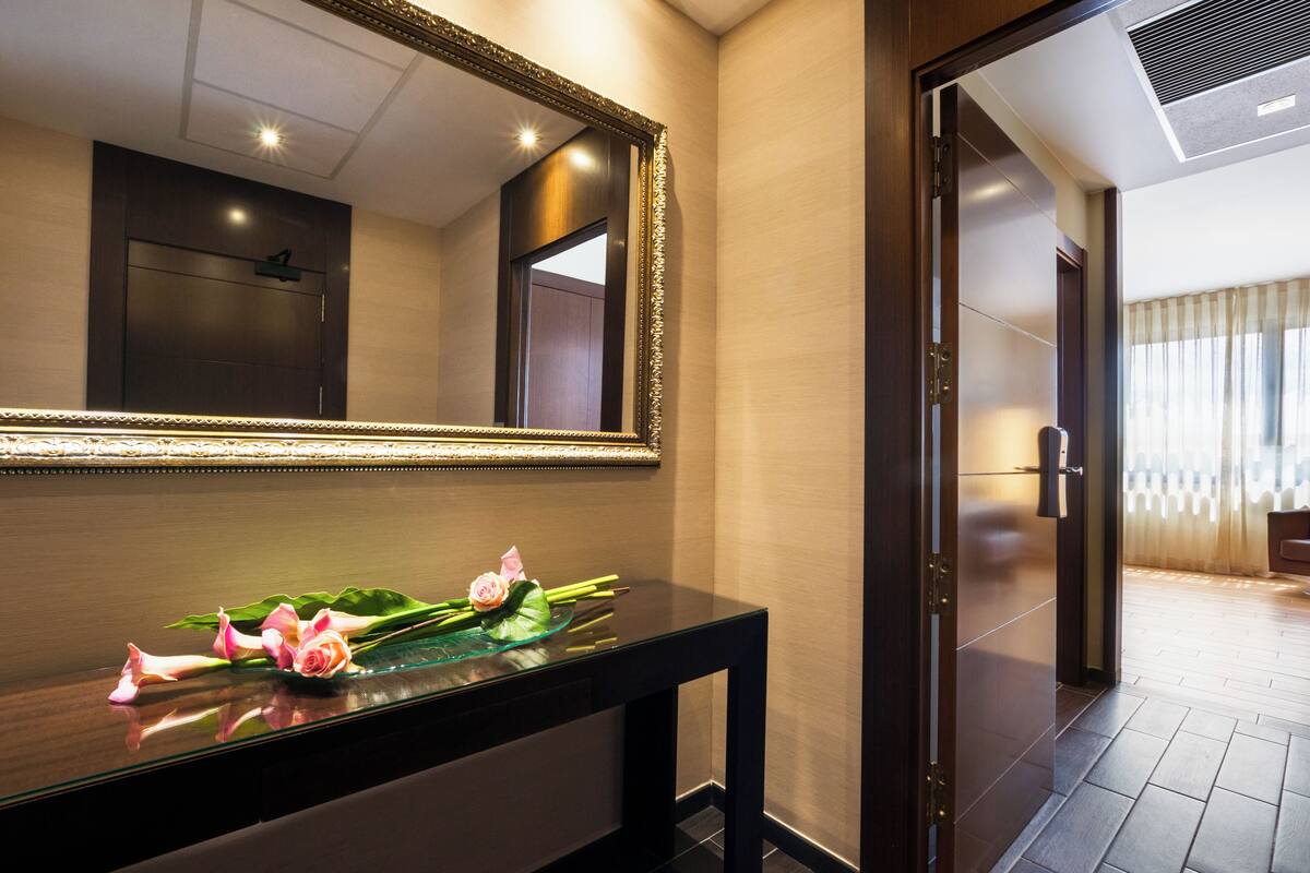 Ein Hotel-Empfangsbereich mit einer Holztresen, einem großen Spiegel und einer dekorativen Blumenkomposition.