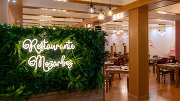 Un interior de restaurante con una pared verde y un letrero de neón que dice 'Restaurant Mozarbez'.