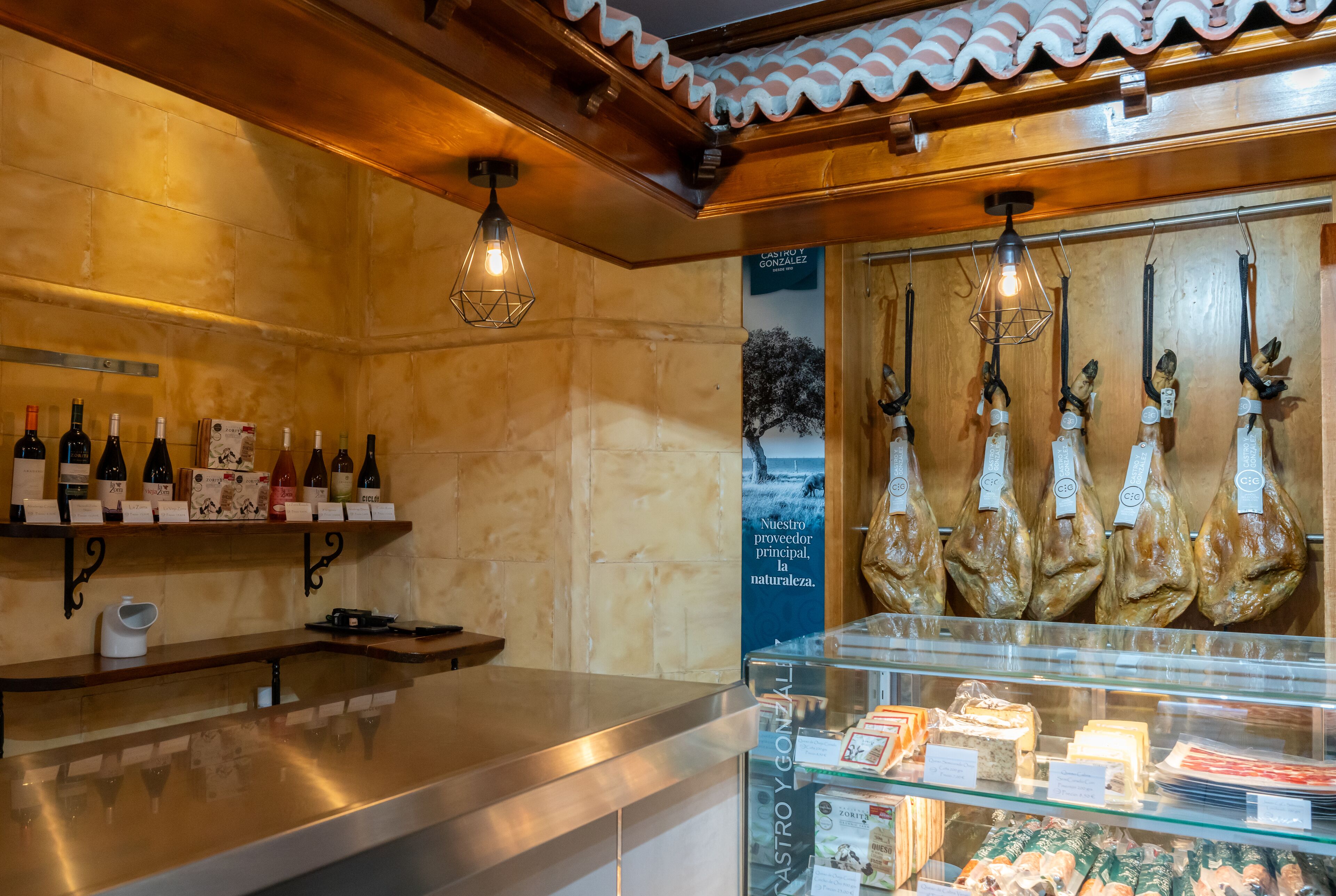 L’intérieur d’un restaurant, avec une étagère à vin, des viandes suspendues et une vitrine réfrigérée.