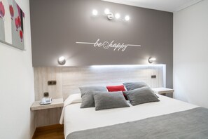 Een moderne hotelkamer met een bed, nachtkastjes, een telefoon en een muur met een 'be happy' bord.