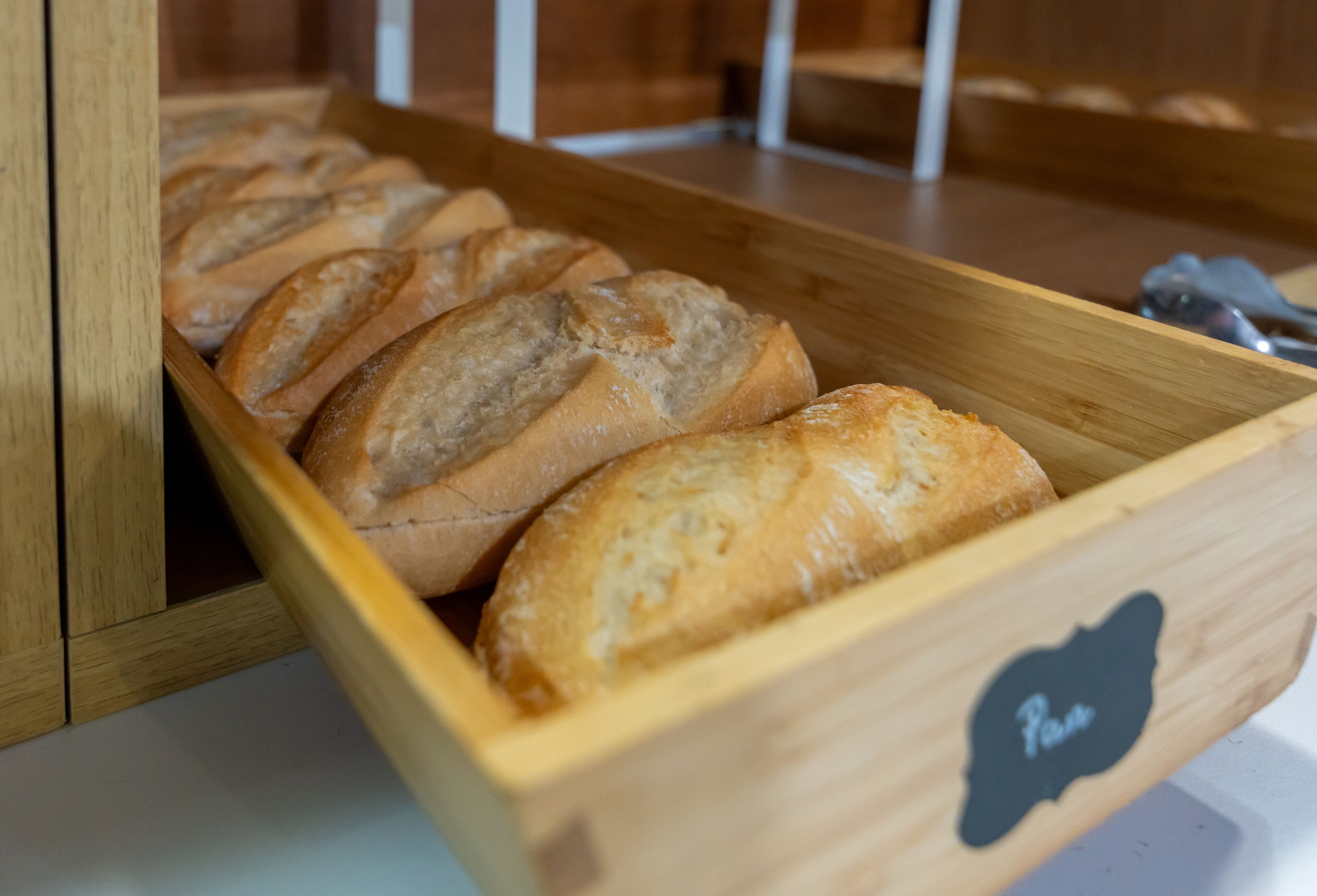 Una caja de madera para pan con una etiqueta, que contiene pan en rebanadas.