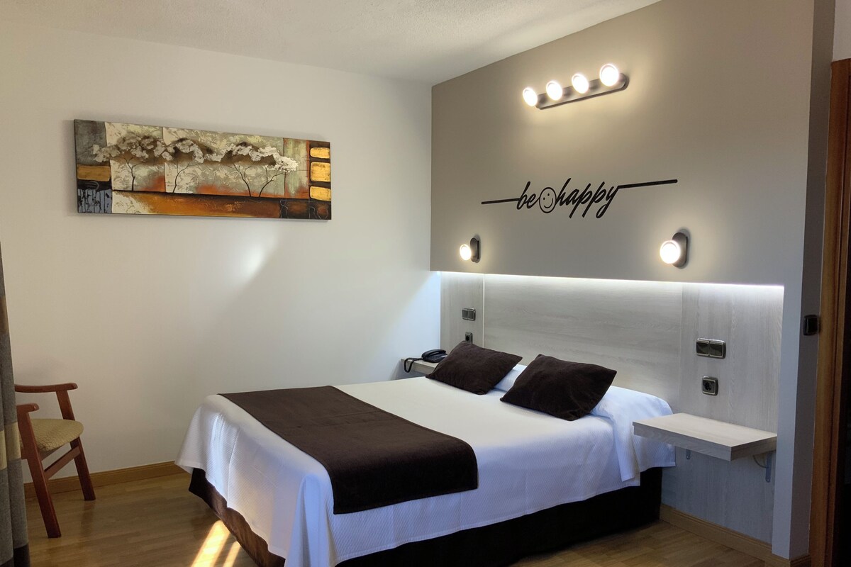 Une chambre d’hôtel avec un lit, une table de chevet, des œuvres d’art mural et une phrase inspirante.