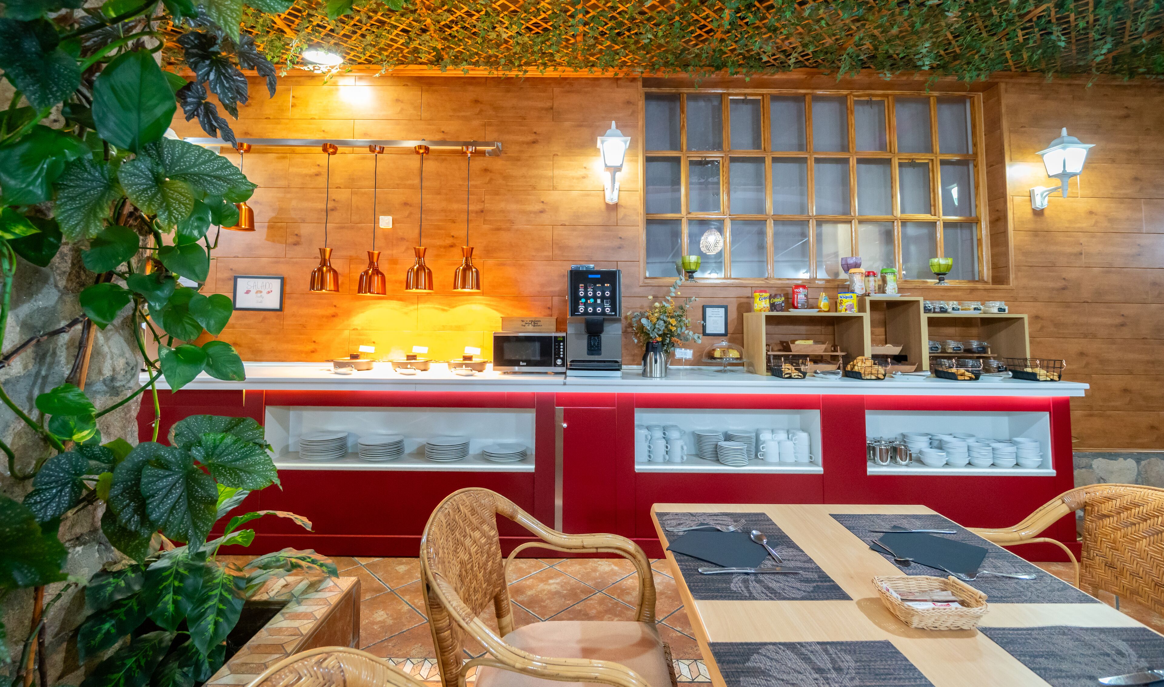 A restaurant with a wooden interior, a counter with a coffee machine, and a window with a view.