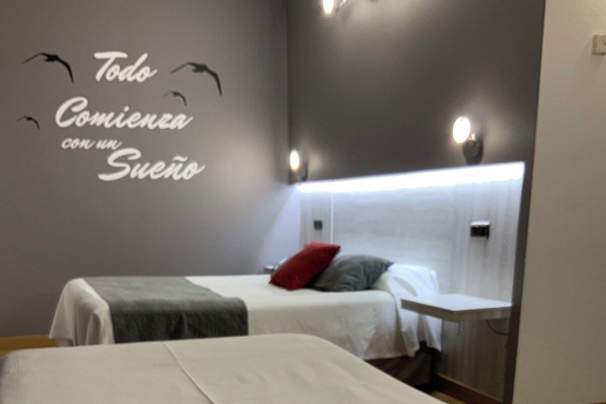 A hotel room with two beds, a large mirror, and a wall with motivational text.