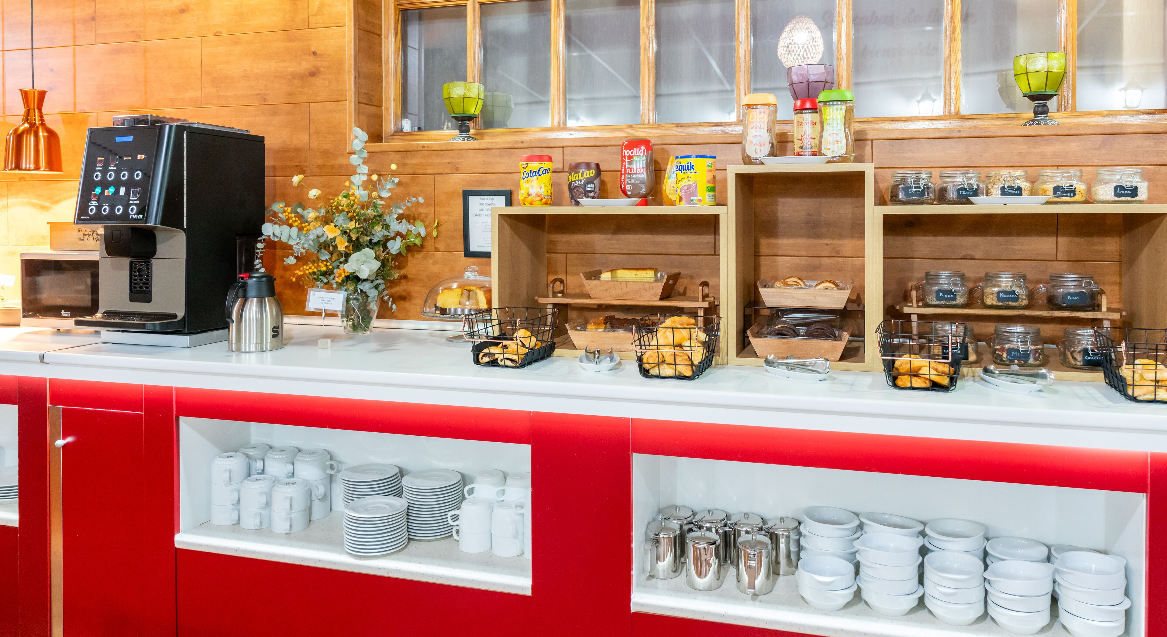 A breakfast bar with a coffee machine, condiments, and pastries.