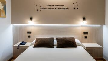 Ein Hotelzimmer mit einem großen Bett, zwei Nachttischen, einem Telefon und einer Wand mit einem Motivationsspruch.
