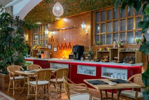 A restaurant with a red counter, wicker chairs, and a brick wall with greenery. - Hotel Mozarbez Salamanca (Mozarbez)