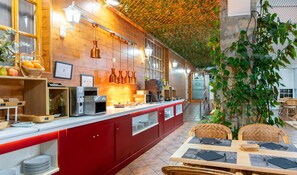 Een restaurant met een rode toonbank, diverse keukenapparaten en een zithoek met rieten stoelen.