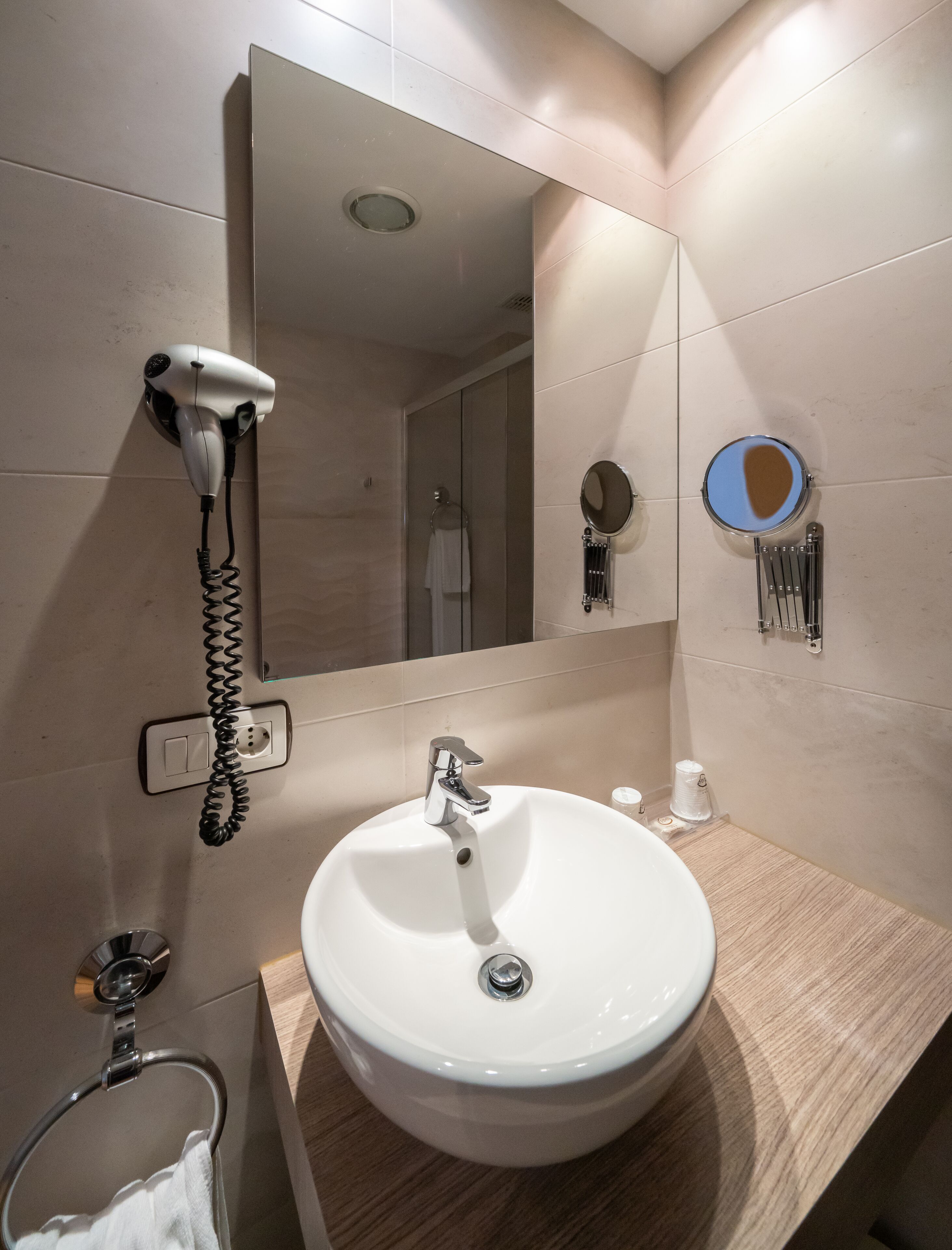 Un baño con lavamanos, espejo, secador de pelo y toallero.