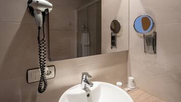 Un baño con lavamanos, espejo, secador de pelo y toallero.