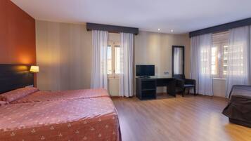 A hotel room with two beds, a desk, a chair, a television, and curtains.