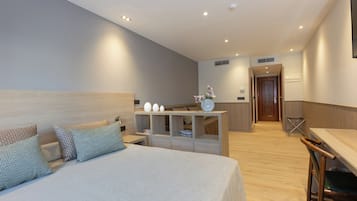 Una habitación de hotel moderna con una cama grande, un escritorio de madera y una zona de kitchenette.