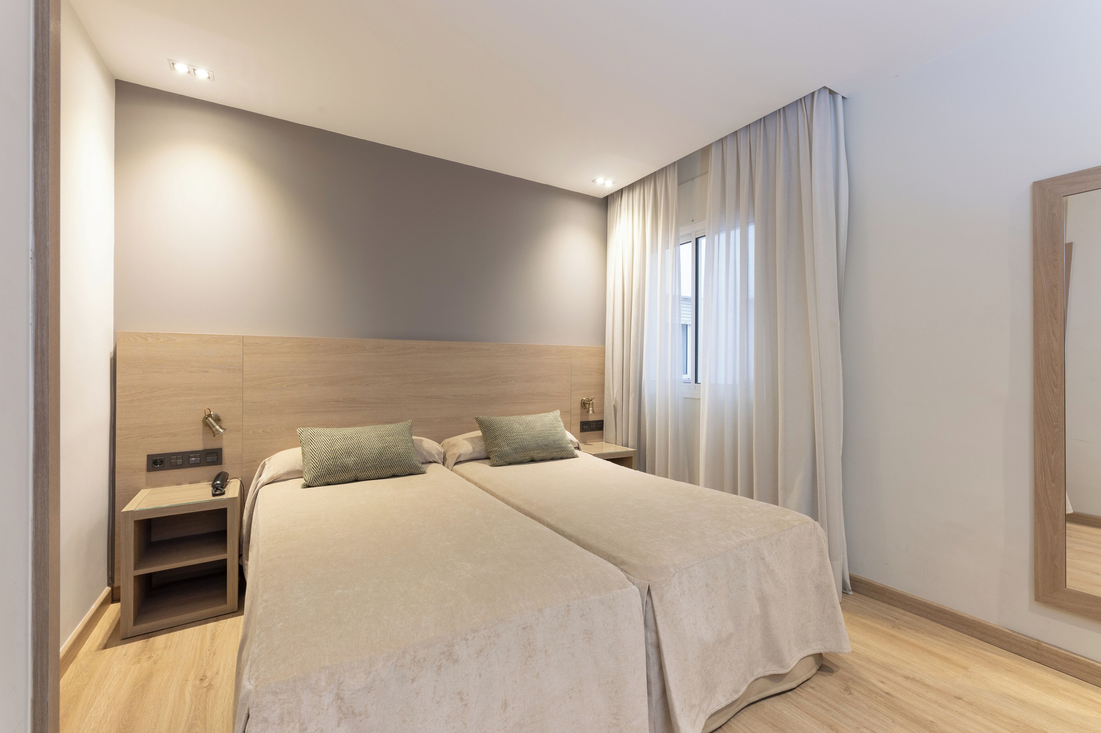Una cama doble con dos almohadas, una mesita de noche con lámpara y un cabecero de madera.
