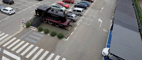 A parking lot with multiple cars and a train engine.