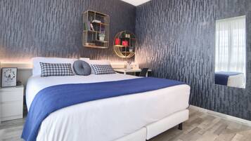 A modern bedroom with a large bed, a desk, and a mirror.