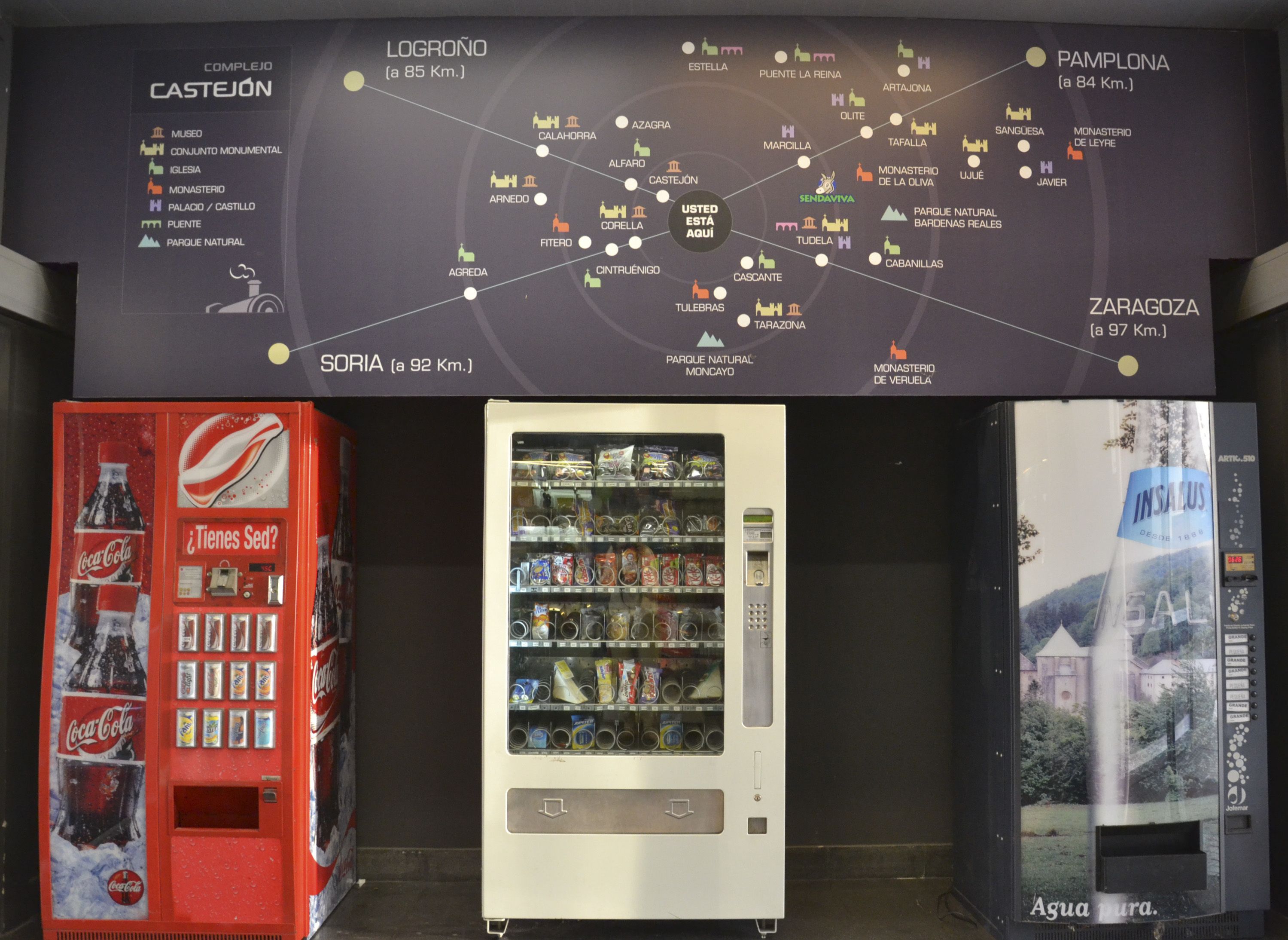 A map with travel destinations and distances, vending machines, and a Coca-Cola advertisement.