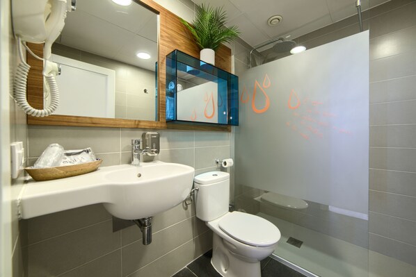 A modern bathroom with a white sink, a toilet, and a glass shower enclosure.