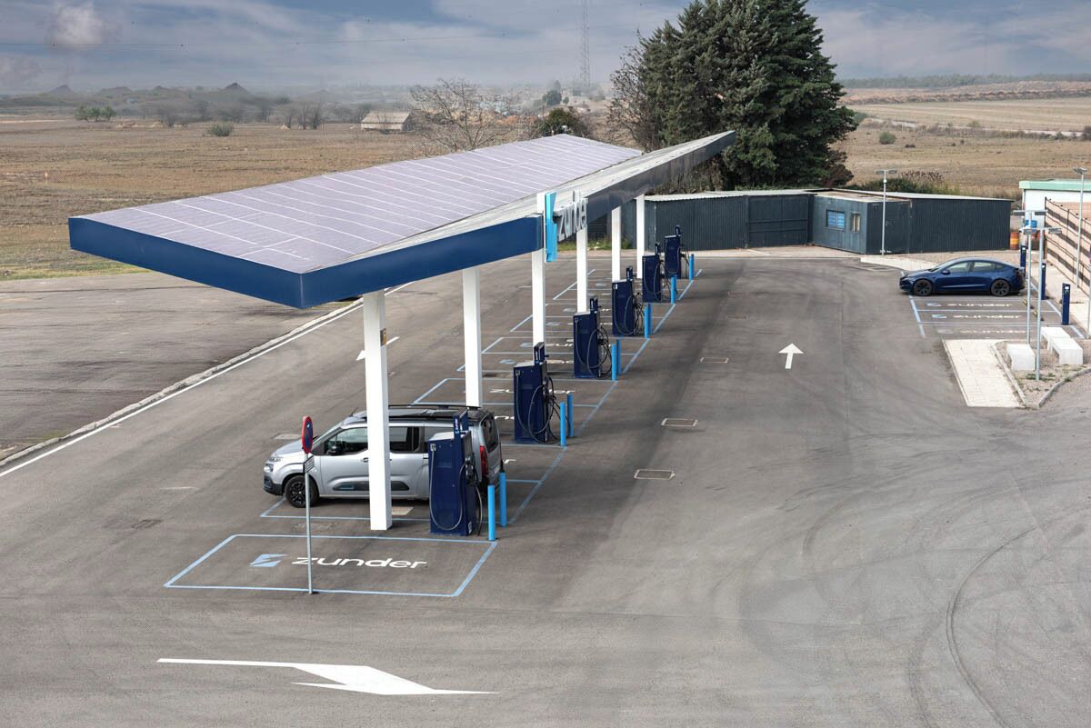 Une station de recharge à énergie solaire dotée de plusieurs bornes de recharge, d’un espace de stationnement couvert et d’un ciel dégagé.