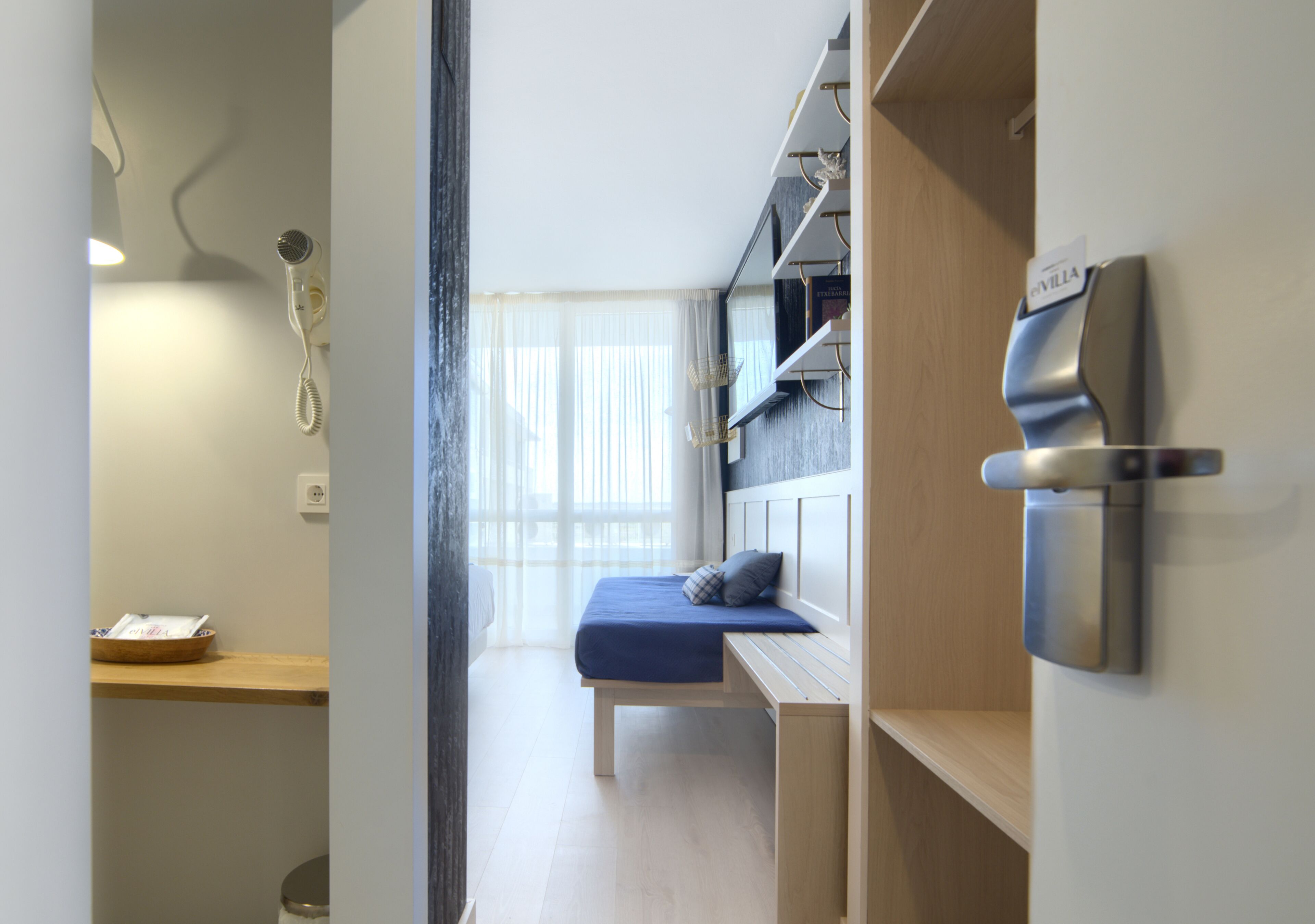 A modern hotel room with a bed, a desk, and a shower.
