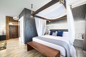 A modern bedroom with a canopy bed, wooden flooring, a bench, and a built-in wardrobe. - Hotel Luze El Villa (Castejón)